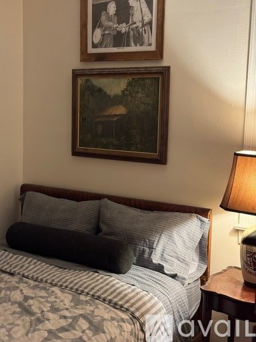 A bed with a striped comforter and a lamp on a side table.