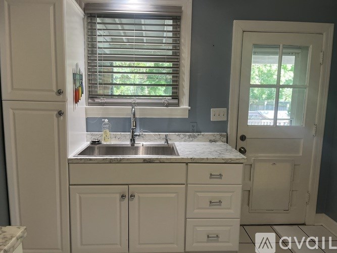 A kitchen with a sink and cabinets under a window.