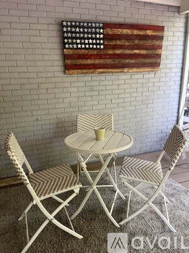 A table with two chairs and an American flag on the wall.
