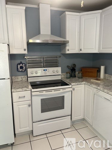 A kitchen with white cabinets and a white stove top oven.