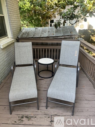 Two grey chairs and a table are on a wooden deck.