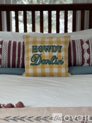 A bed with a pillow that says "Howdy Dan'l" on it.
