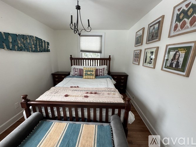 A bedroom with a bed, a chandelier, and pictures on the wall.