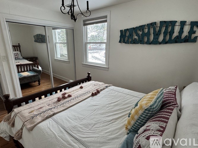 A bedroom with a bed, a chandelier, and a wall decoration that says Nashville.