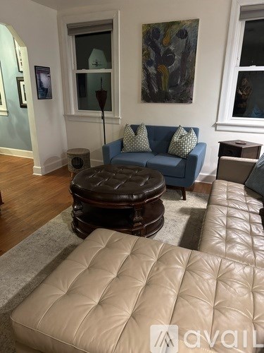 A living room with a blue couch and a brown ottoman.