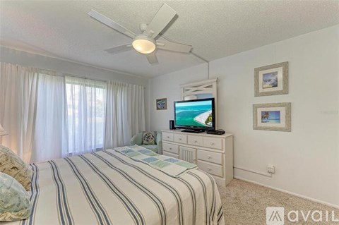 A bedroom with a bed, a television, and a ceiling fan.