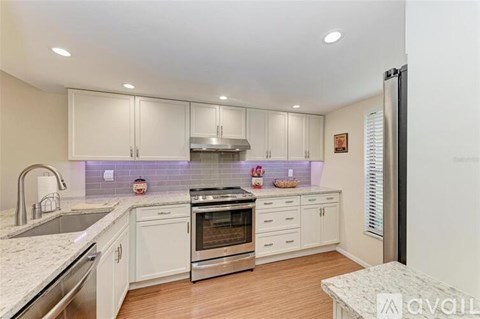 A kitchen with white cabinets and a stainless steel refrigerator.