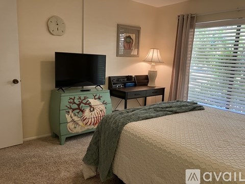 A bedroom with a bed, a dresser, a desk, and a window with blinds.