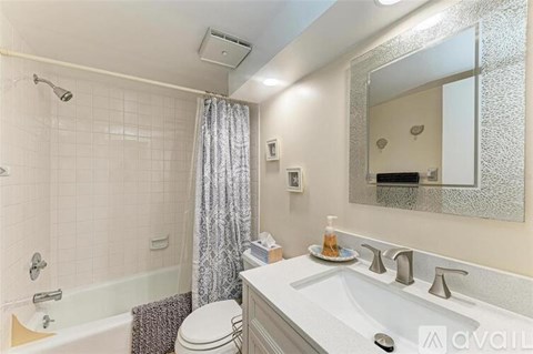 A bathroom with a white sink, toilet, and a shower with a curtain.