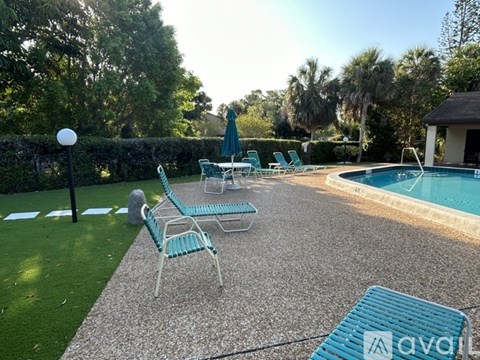 A backyard with a pool and lounge chairs.