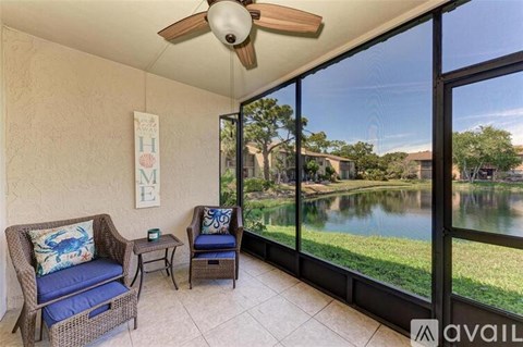 A patio with a chair and a table with a view of a lake.