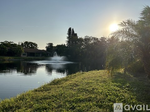A fountain in the middle of a lake surrounded by greenery.