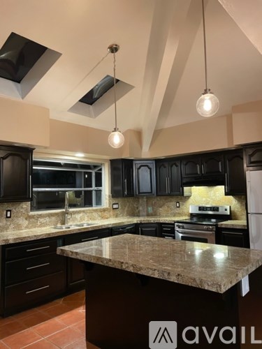A kitchen with black cabinets and a granite countertop.