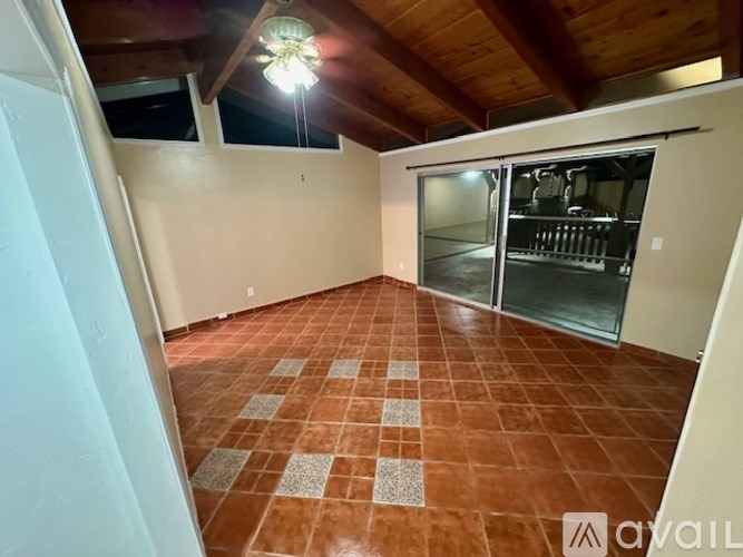 A room with a tiled floor and a refrigerator on the left side.