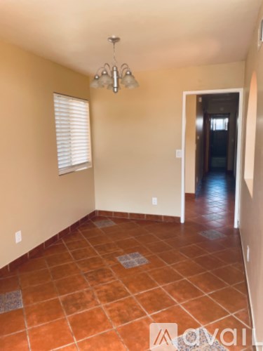 A room with a chandelier, tiled floor, and a doorway leading to another room.