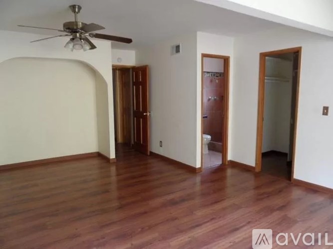 A room with a ceiling fan and wooden floors.