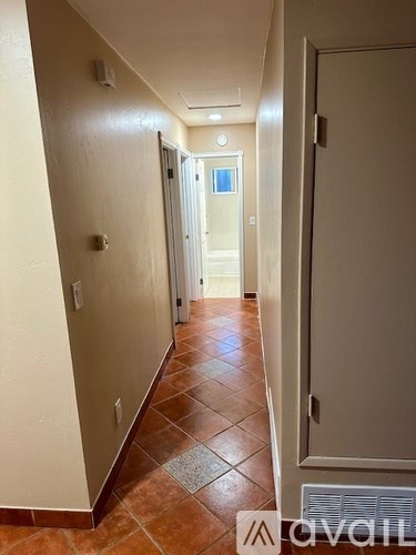 A hallway with tiled floors and white walls.
