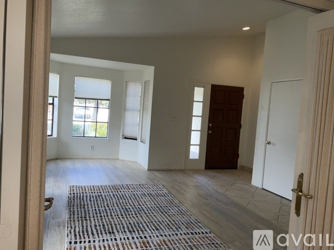 A room with a rug on the floor and a door on the right.