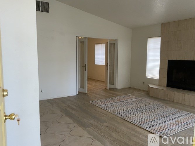 A room with a rug on the floor and a door in the background.
