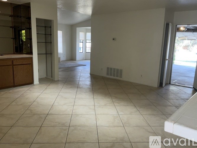 A spacious room with tiled flooring and a cabinet on the left side.
