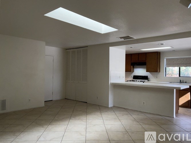 A spacious kitchen with white cabinets and a skylight.