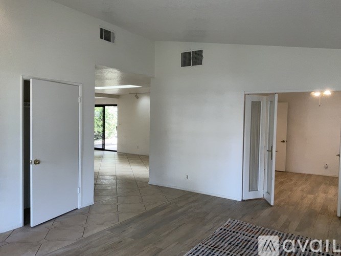 A room with a white door and a window with a view of trees.