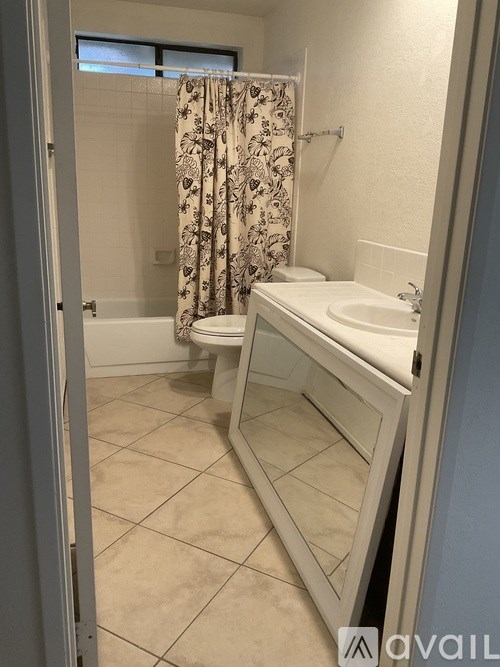 A bathroom with a white sink and a shower with a floral shower curtain.