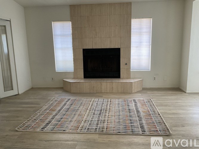 A living room with a fireplace and a rug on the floor.