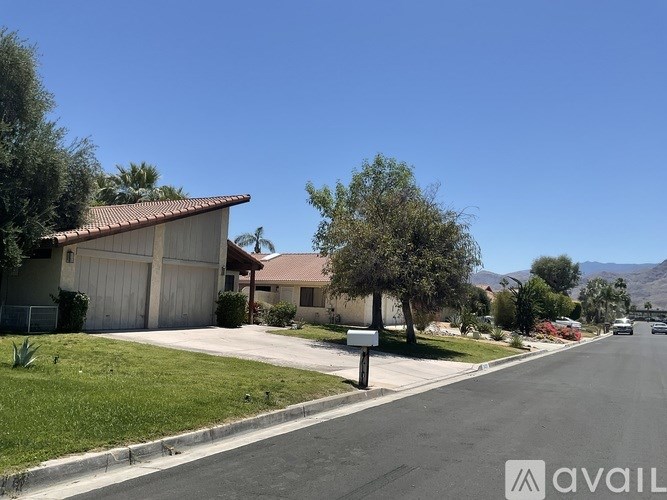 A residential street with houses on both sides and a clear blue sky.
