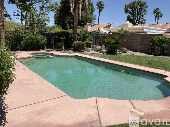 A pool surrounded by a concrete patio and a green lawn.