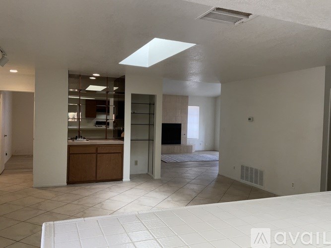 A spacious living room with a kitchen in the background.