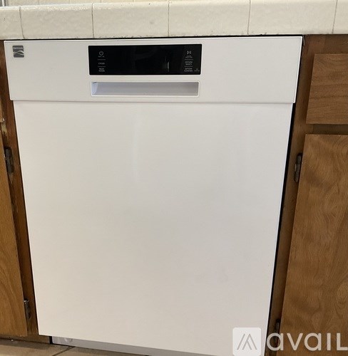 A white dishwasher with a black control panel is in a kitchen.