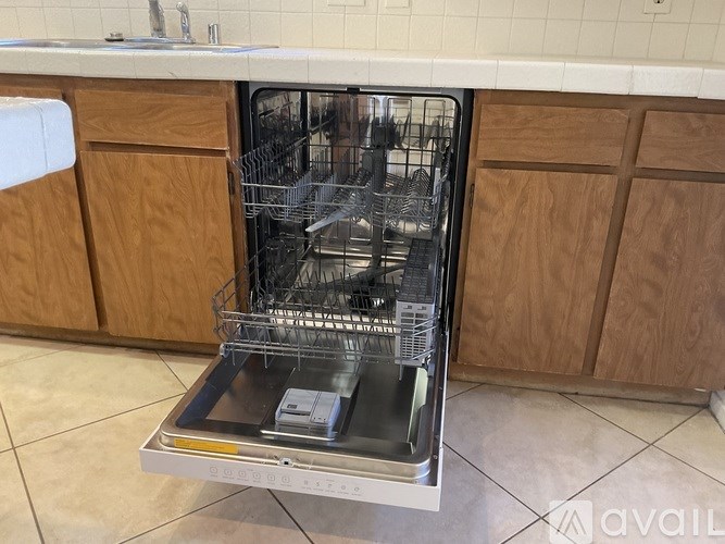 A dishwasher is open and empty in a kitchen.