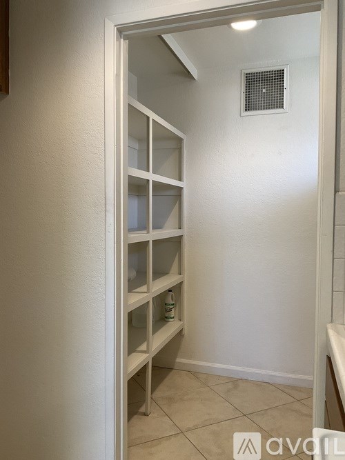 A white doorway with a shelf and a vent on the wall.