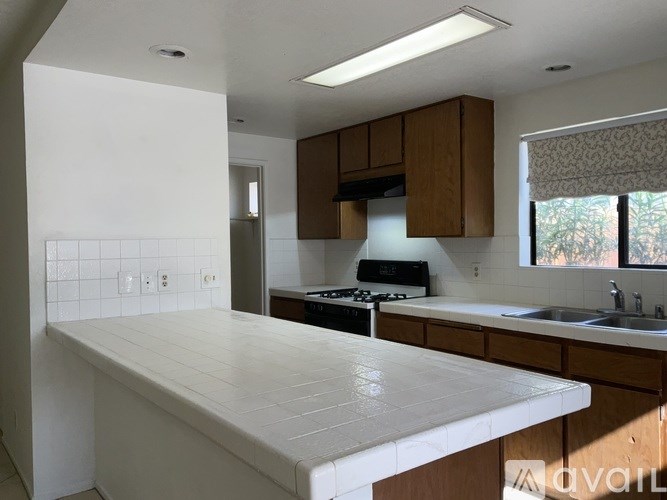 A kitchen with a white countertop and wooden cabinets.