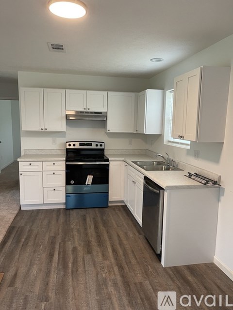 A kitchen with white cabinets and a wooden floor.