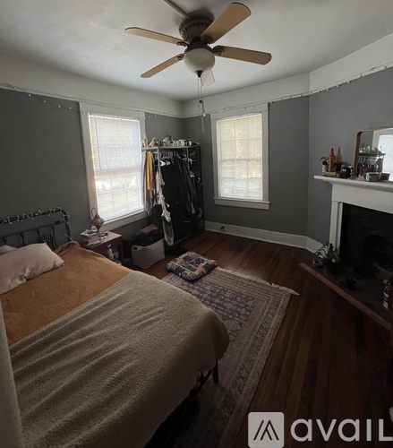 A bedroom with a bed, a fireplace, and a ceiling fan.