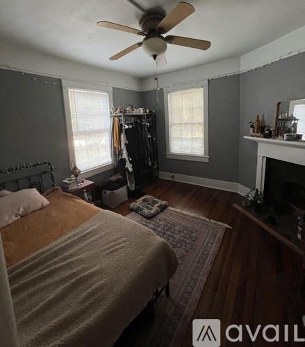 A bedroom with a bed, a fireplace, and a ceiling fan.