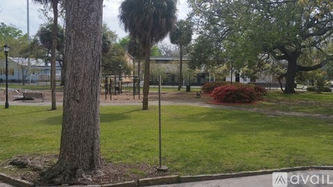 A park with a tree in the foreground and a building in the background.