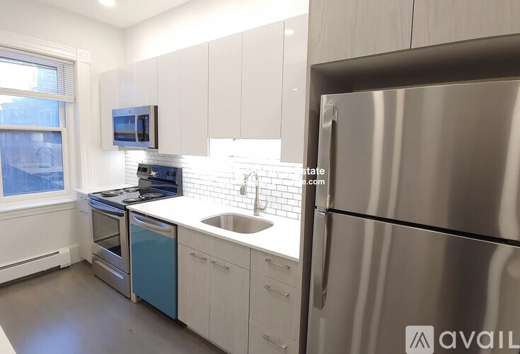 A modern kitchen with a stainless steel refrigerator and white cabinets.