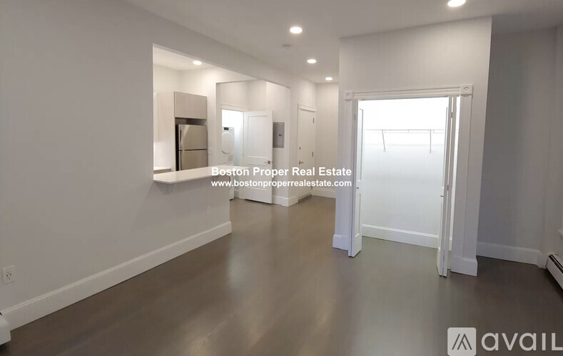 A spacious empty room with a door on the right side.