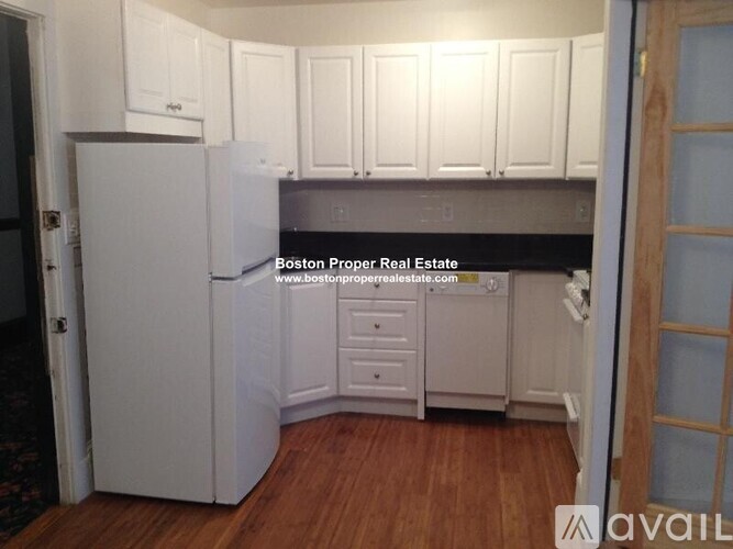 A kitchen with white cabinets and a refrigerator.