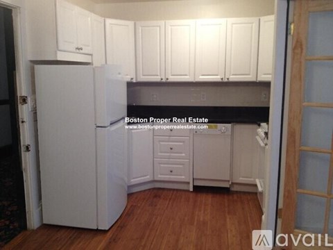 A kitchen with white cabinets and a refrigerator.