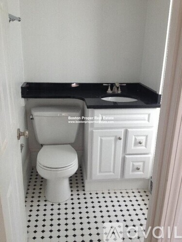 A white toilet sits in a bathroom with a black counter top.