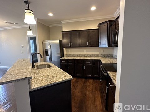 A kitchen with a granite countertop and dark brown cabinets.