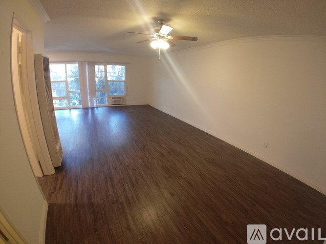 A spacious room with wooden flooring and a ceiling fan.