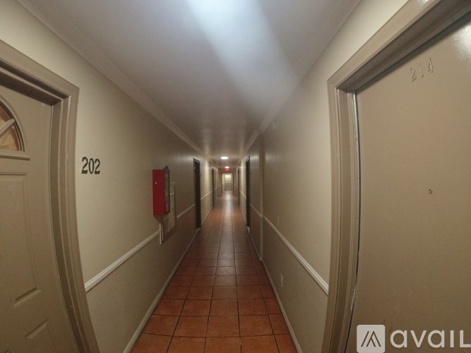 A long hallway with doors on either side and a red fire extinguisher in the middle.