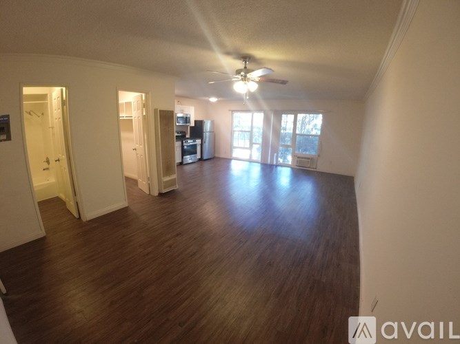 A spacious room with wooden floors and a ceiling fan.