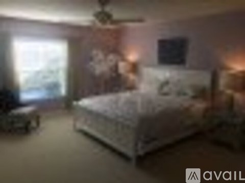 A bedroom with a bed, a chair, and a ceiling fan.
