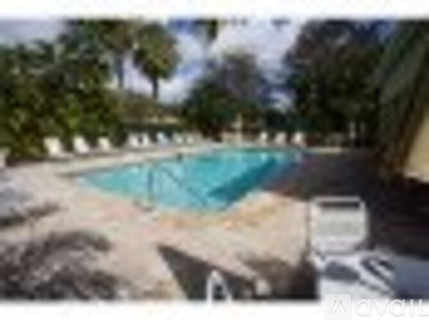A pool surrounded by trees and a white fence.